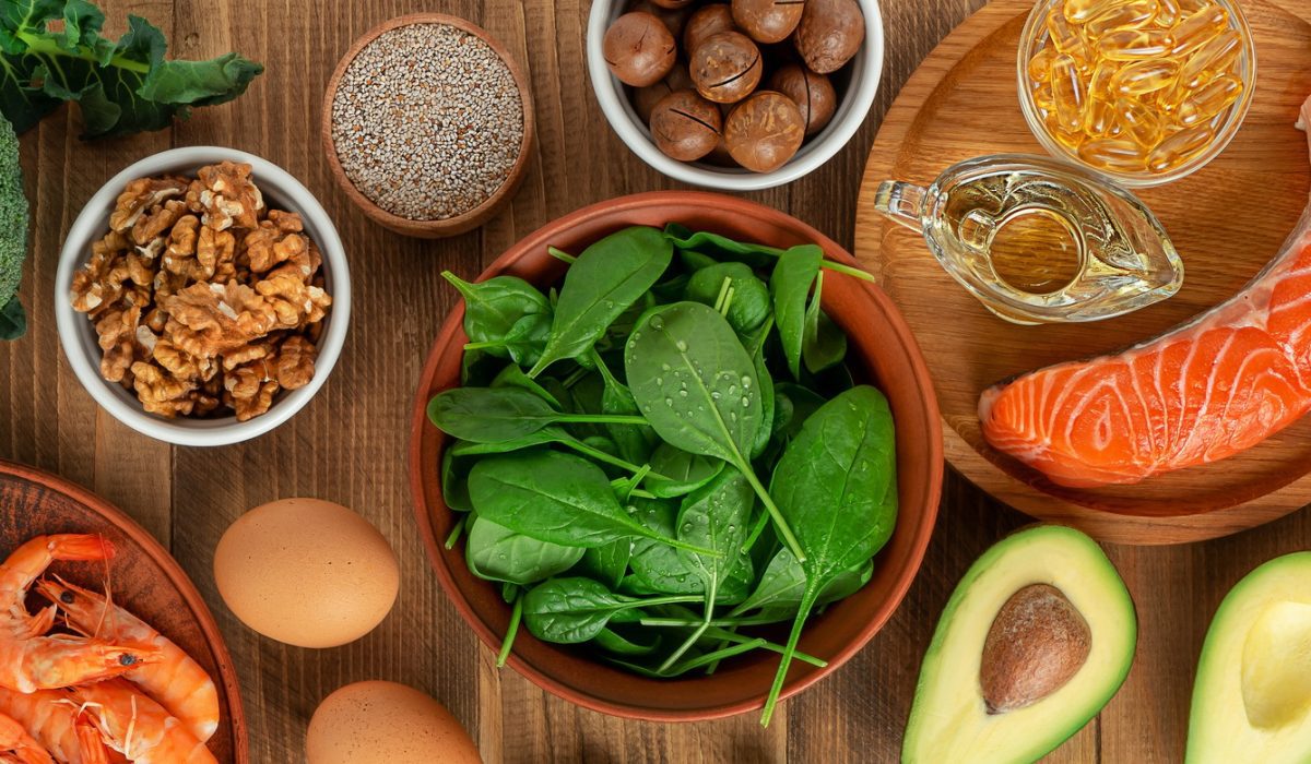 A vibrant flat lay of B12-rich superfoods, including salmon, eggs, dairy products, clams, sardines, beef liver, fortified nutritional yeast, and leafy greens, arranged on a rustic wooden table. The ingredients are fresh and colorful, representing optimal sources of Vitamin B12.
