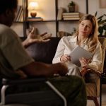 Overwhelmed female therapist surrounded by paperwork and admin tasks in her private practice office.
